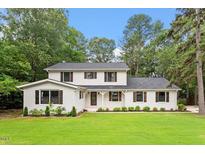 Charming two-story home features a manicured lawn, lush landscaping, and a classic white exterior at 4109 Pepperton Dr, Raleigh, NC 27606