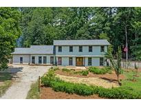 Charming two-story home featuring a landscaped front yard with mature trees offering ample shade and privacy at 5209 Amsterdam Pl, Raleigh, NC 27606