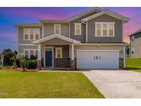 Two-story home featuring a blue front door and an attached two-car garage with verdant lawn at 812 Teal Lake Dr, Holly Springs, NC 27540