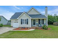 Charming single Gathering home features a well-manicured lawn, tidy landscaping, and a cozy front porch at 104 Roscommon Ln, Clayton, NC 27520