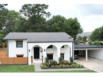 Charming white-brick home with modern arched entryway, carport, and lush landscaping at 1523 Ivy Ln, Raleigh, NC 27609
