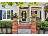 Inviting front entrance with brick pillars, flower pots, and a black front door with sidelights at 1705 Green Oaks Pkwy, Holly Springs, NC 27540