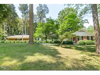 Charming brick home featuring a lush green lawn and mature trees offering ample shade at 225 Bellwood Dr, Henderson, NC 27536