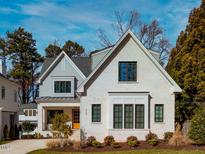 Striking two-story home featuring a white brick facade, black framed windows, gabled roof, and manicured landscaping at 2300 Lyon St, Raleigh, NC 27608