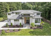 Stunning front exterior with stone accents, a modern double-door entrance, and lush, professionally landscaped yard at 213 Westhampton Dr, Pittsboro, NC 27312