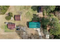 Aerial view of the house with a green roof, sheds, detached garage, and a long driveway in a wooded setting at 5027 Lake Willett Rd, Sanford, NC 27332