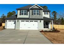 Two-story house with gray siding, three-car garage, and landscaped yard at 35 Fort Mcclary Ct, Cameron, NC 28326