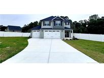 Charming two-story home showcasing a well-manicured lawn, a double garage, and complemented by a pristine white fence at 35 Fort Mcclary Ct, Cameron, NC 28326