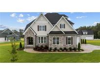 Two-story home boasts a stone and gray siding exterior, complemented by a lush green lawn and manicured landscaping at 25 Cotton Fields Ln, Fuquay Varina, NC 27526