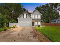 Charming two-story home featuring a manicured lawn, two-car garage and inviting front porch at 60 Hunters Way, Angier, NC 27501