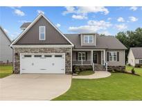 Charming two-story home boasts a stone facade, two-car garage, and a well-manicured front yard at 75 Woodbark Cv # 10, Willow Springs, NC 27592