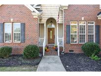 Charming brick home featuring a beautiful front door framed by decorative shrubs and seasonal accents at 9404 Perimeter Ct, Zebulon, NC 27597