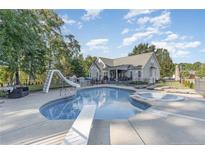Backyard pool with diving board, slide, and hot tub offers a fun outdoor living space at 9404 Perimeter Ct, Zebulon, NC 27597