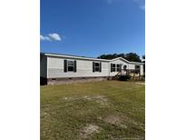 Charming single-story home with gray siding, black shutters, and a well-maintained front yard at 16 Industrial Dr, Bunnlevel, NC 28323