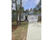 Charming single-story home featuring a two-car garage, a well-manicured lawn, and attractive neutral siding at 8027 Royal Dr, Sanford, NC 27332