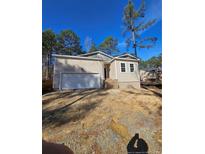 Home exterior with a two-car garage and partially landscaped front yard in a wooded community at 8030 Turnberry Cir, Sanford, NC 27332