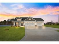 Charming single-Gathering home boasts a manicured lawn and long driveway leading to a three-car garage at 32 Boyce Ct, Sanford, NC 27332