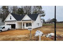 Newly constructed home with a white exterior, black roof, and attached garage at 123 Nectar Ln, Bunnlevel, NC 28323