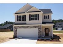 Charming two-story home features a stone accent, a two-car garage and a manicured lawn at 154 Nectar Ln, Bunnlevel, NC 28323
