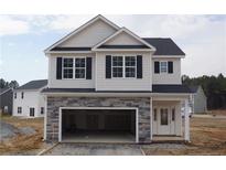 Two-story home with a stone-accented garage, a symmetrical facade, and black window shutters at 154 Nectar Ln, Bunnlevel, NC 28323