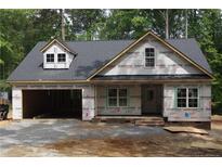 New construction home with a two-car garage showcasing modern architectural design and an unfinished yard at 2194 Cleveland Cir, Sanford, NC 27332