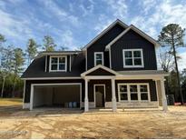 Two-story farmhouse exterior boasts dark siding, a large garage, and a welcoming front porch at 6935 Old Jefferson Davis Hwy, Cameron, NC 28326