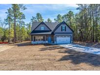 Charming gray two-story home with black accents, a two-car garage, and beautifully landscaped front yard at 6967 Old Jefferson Davis Hwy, Cameron, NC 28326