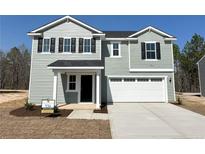 Charming two-story home featuring a two-car garage and a well-manicured front yard at 57 Bennington Way, Lillington, NC 27546