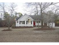 Beige house with red door, landscaping, and detached shed at 357 Juno Dr, Broadway, NC 27505