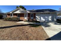 Brick ranch house with attached garage and landscaped yard at 307 Westfield Dr, Dunn, NC 28334