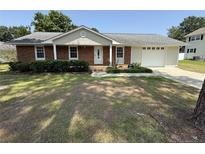 Charming single-story brick home featuring a well-manicured lawn, attached garage and inviting front entrance at 307 Westfield Dr, Dunn, NC 28334