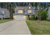 Two-story gray house with white garage door, landscaping, and a driveway at 165 Timber Skip Dr, Spring Lake, NC 28390