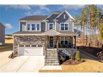 Two-story home with stone accents and a three-car garage at 174 High Woods Rdg, Chapel Hill, NC 27517