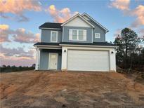 Charming two-story home featuring a blue exterior, white trim, and an attached two-car garage at 17 Tackett Ct, Lillington, NC 27546