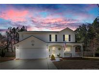 Charming two-story home with a front porch, two-car garage and beautifully landscaped yard under a colorful sky at 511 Providence Hall Dr, Sanford, NC 27330