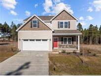 Two-story house with a red door, attached garage, and stone accents at 551 Stadium Dr, Cameron, NC 28326