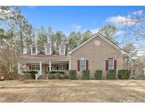 Charming brick home featuring dormer windows, a covered porch, and meticulously manicured landscaping at 61 Fountain Park Cir, Spring Lake, NC 28390