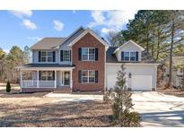 Two-story brick and siding house with attached two-car garage and front porch at 145 Rolling Stone Ct, Sanford, NC 27332