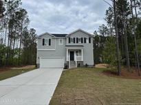 Two-story home featuring a two-car garage, gray siding, black shutters, and professionally landscaped yard at 122 Horse Trot Ln, Sanford, NC 27332