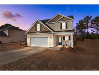 Two-story house with a tan exterior, white garage door, and rocking chairs on the porch at 129 Parkview Ln, Lillington, NC 27546