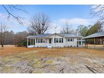 Charming single-story home with green shutters, a covered front porch, and a carport on a grassy lot at 4410 Cox Mill Rd, Sanford, NC 27332