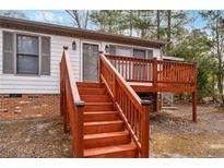 Inviting home exterior featuring a wooden deck with matching stairs leading to the front door at 5802 Lillie Dr, Durham, NC 27712