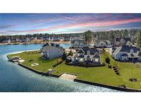 Stunning aerial view of waterfront homes on lush green lawns by a serene lake with docks at 107 Pelican Ct, Sanford, NC 27332