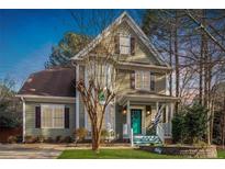 Charming two-story home with a manicured lawn, bay window, and inviting front porch with a distinctive turquoise door at 214 Pine Nut Ln, Apex, NC 27502