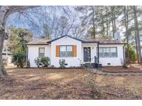 Charming renovated single-story home with white painted brick, contrasting trim, and mature trees at 711 Horton Rd, Durham, NC 27704