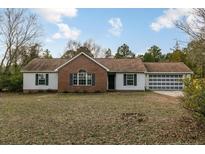 Charming one-story home featuring a brick accent wall, a well-maintained lawn and an attached two car garage at 1425 Ponderosa Trl, Cameron, NC 28326