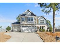 Charming two-story home with a three-car garage and inviting front porch and a blue sky background at 38 Heatherwood Dr, Lillington, NC 27546