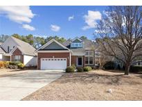 Charming brick home featuring a two-car garage, well-manicured landscaping, and a welcoming entrance at 98 Cottswold Ln, Spring Lake, NC 28390