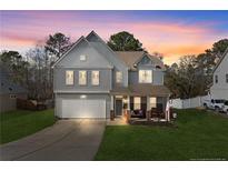 Charming two-story home with a well-manicured lawn and inviting front porch at dusk at 334 Heathrow Dr, Spring Lake, NC 28390