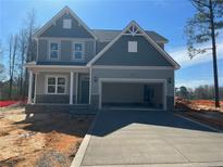 Charming two-story home featuring a two-car garage and stone accents on the facade, set against a blue sky at 22 Peach Orchard (Lot 1) Ln, Lillington, NC 27546